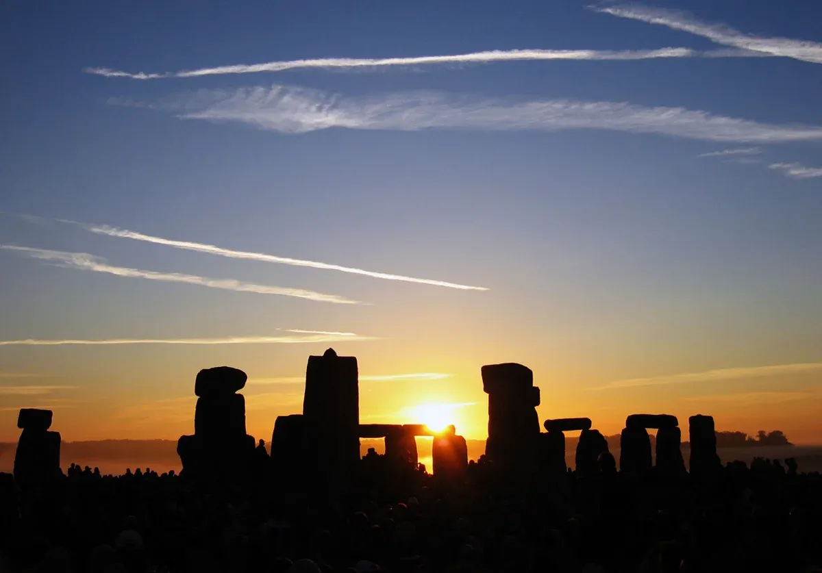 Summer solstice sunrise behind the Heel Stone at Stonehenge, reached from London, Wiltshire